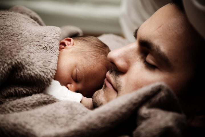 close up of a dad and his little baby sleeping together