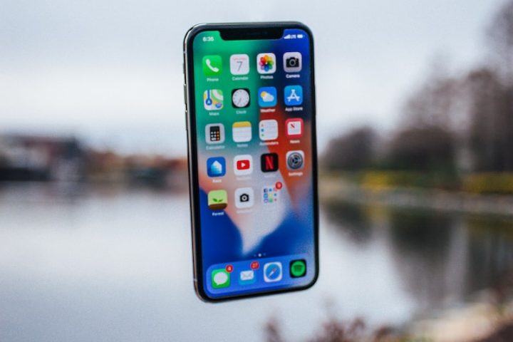 silver iPhone X floating over open palm