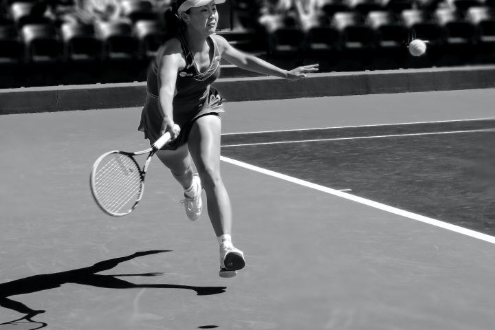 grayscale photo of woman playing tennis